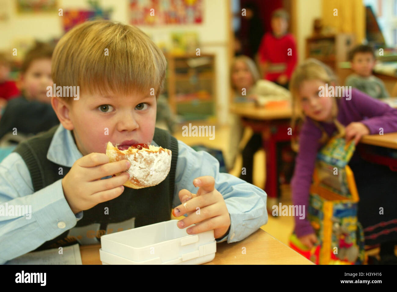 Aule, break, boy, ciambella, mangiare a scuola, le lezioni, banco di scuola, bambino, scolaro, scuola per bambini, 7 anni, la fame, torte, torte e pasticcini, candy, ricco di calorie, poveri di nutrienti, fattener, contenenti zucchero, nutrizione, unhealthily, "spezzare il pane", pennino Foto Stock