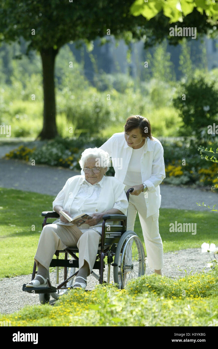 Senior, non valido, sedia a rotelle, libro, leggere, old nurse, spingere, a piedi, intrattenimento anziani in casa, vecchia casa di riposo, Senior Citizen's home, giardino, parco, donna vecchia, vecchia persona titolare di pensione o di rendita, il titolare di pensione o di rendita, infermiere, mantenuta, per andare a piedi, preoccupazione care, aiuto Foto Stock