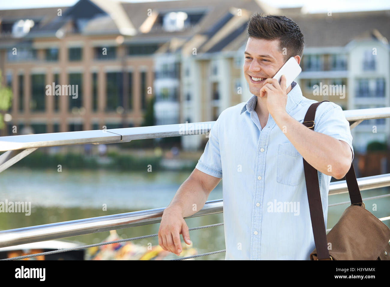 Giovane uomo rendendo chiamata sul telefono cellulare per raggiungere a piedi i lavori Foto Stock