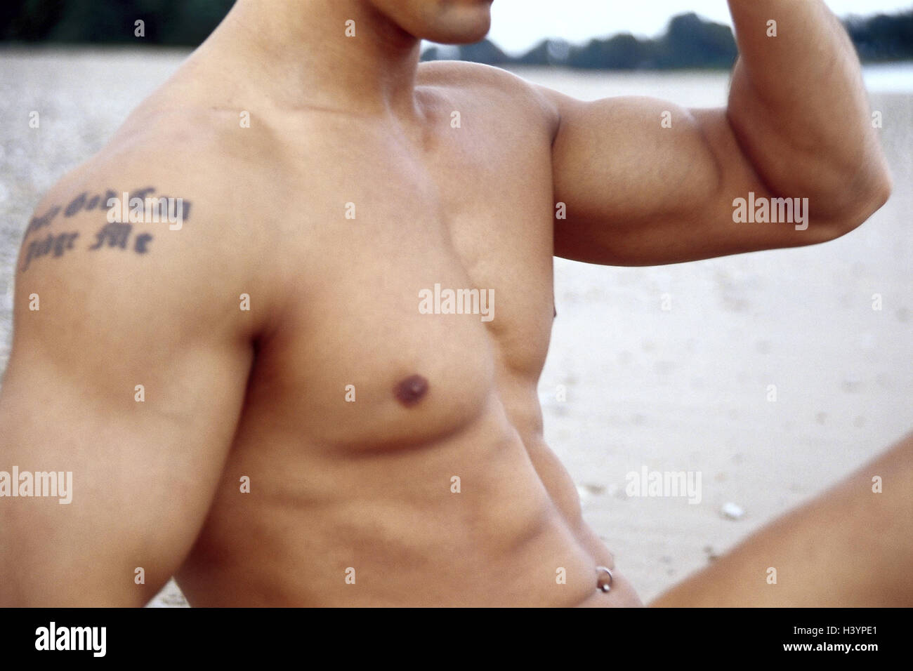Spiaggia, l uomo e la parte superiore del corpo, tatuaggi, piercing all' ombelico, seduti, il gesto, dettaglio Foto stock - Alamy