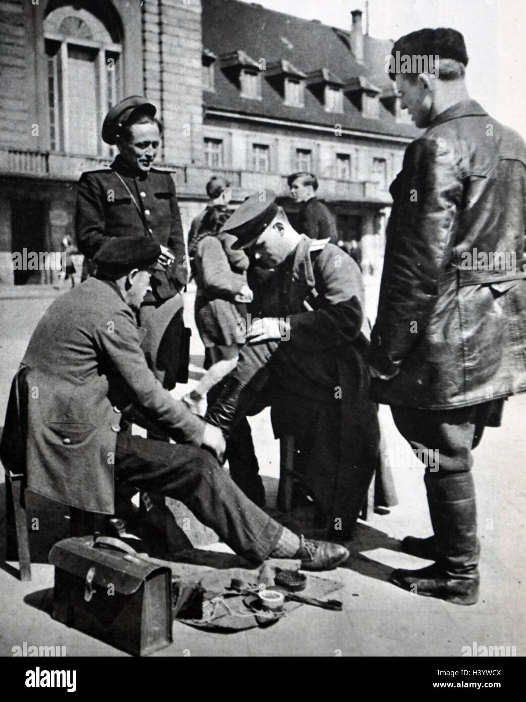 Fotografia di un soldato dell'esercito rosso avente le sue scarpe lucidati con un uomo tedesco. In data xx secolo Foto Stock