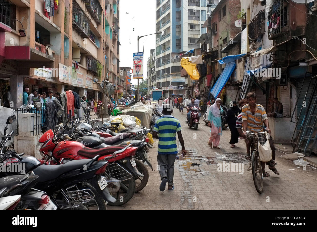Moto parcheggiata sulla strada e le persone che si recano sulle loro attività quotidiane. Scene di strada dharavi, Mumbai, India Foto Stock