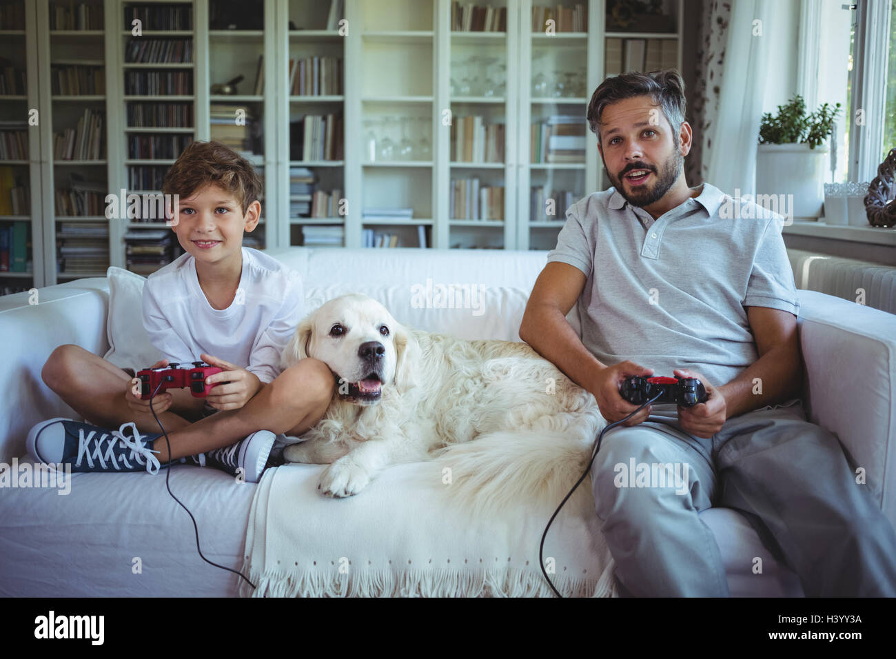 Padre e Figlio seduto sul divano con il cane e la riproduzione di video giochi Foto Stock