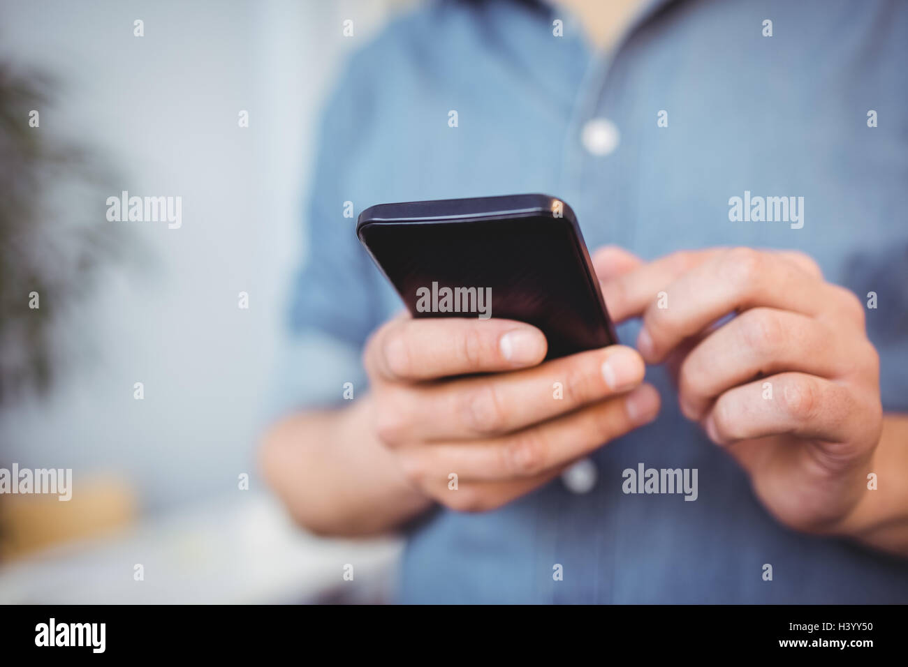 Sezione mediana di imprenditore sms sul cellulare presso il creative office Foto Stock