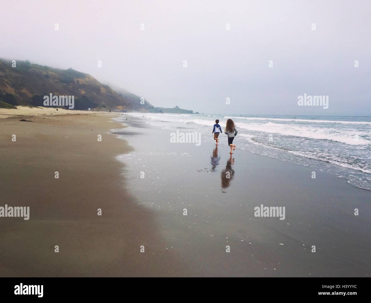 Ragazzo e ragazza che corre lungo la spiaggia, Latacunga, Ecuador Foto Stock