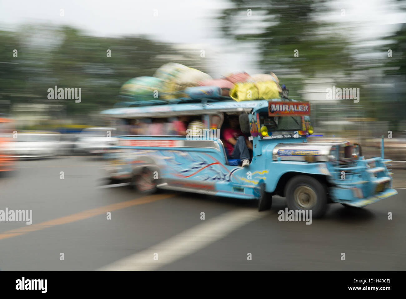 Bassa velocità dell'otturatore della fotocamera esagerando il movimento di un Jeepney di veicoli per il trasporto pubblico a Cebu City, nelle Filippine. Foto Stock