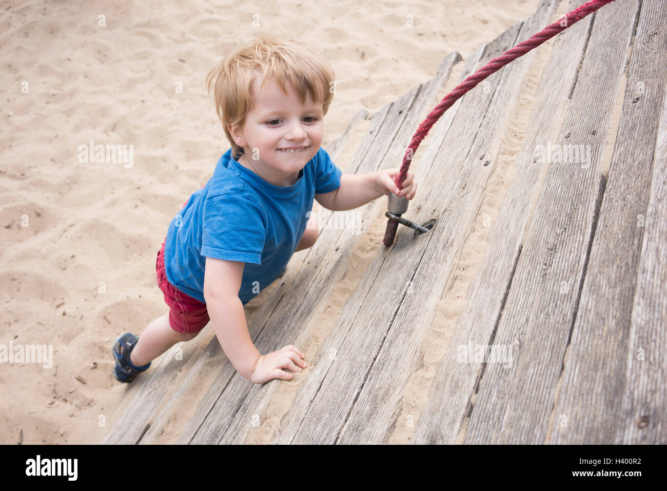 Angolo di Alta Vista del ragazzo sorridente tenendo la corda al parco giochi Foto Stock