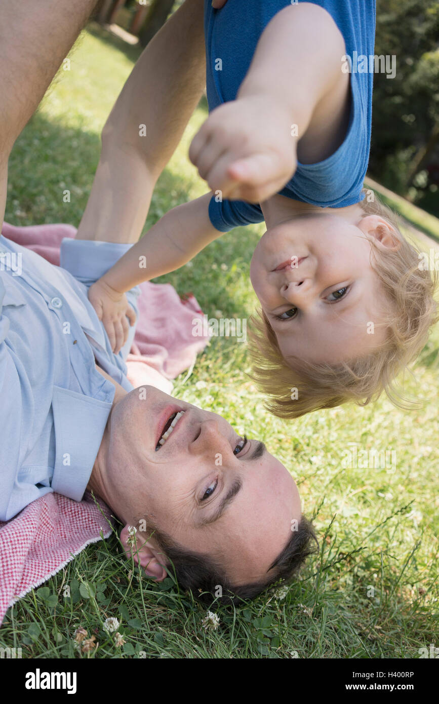 Ritratto di padre figlio di sollevamento sdraiati sull'erba Foto Stock