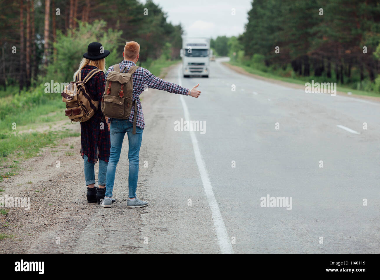 Vista posteriore del giovane autostop sulla strada contro alberi Foto Stock