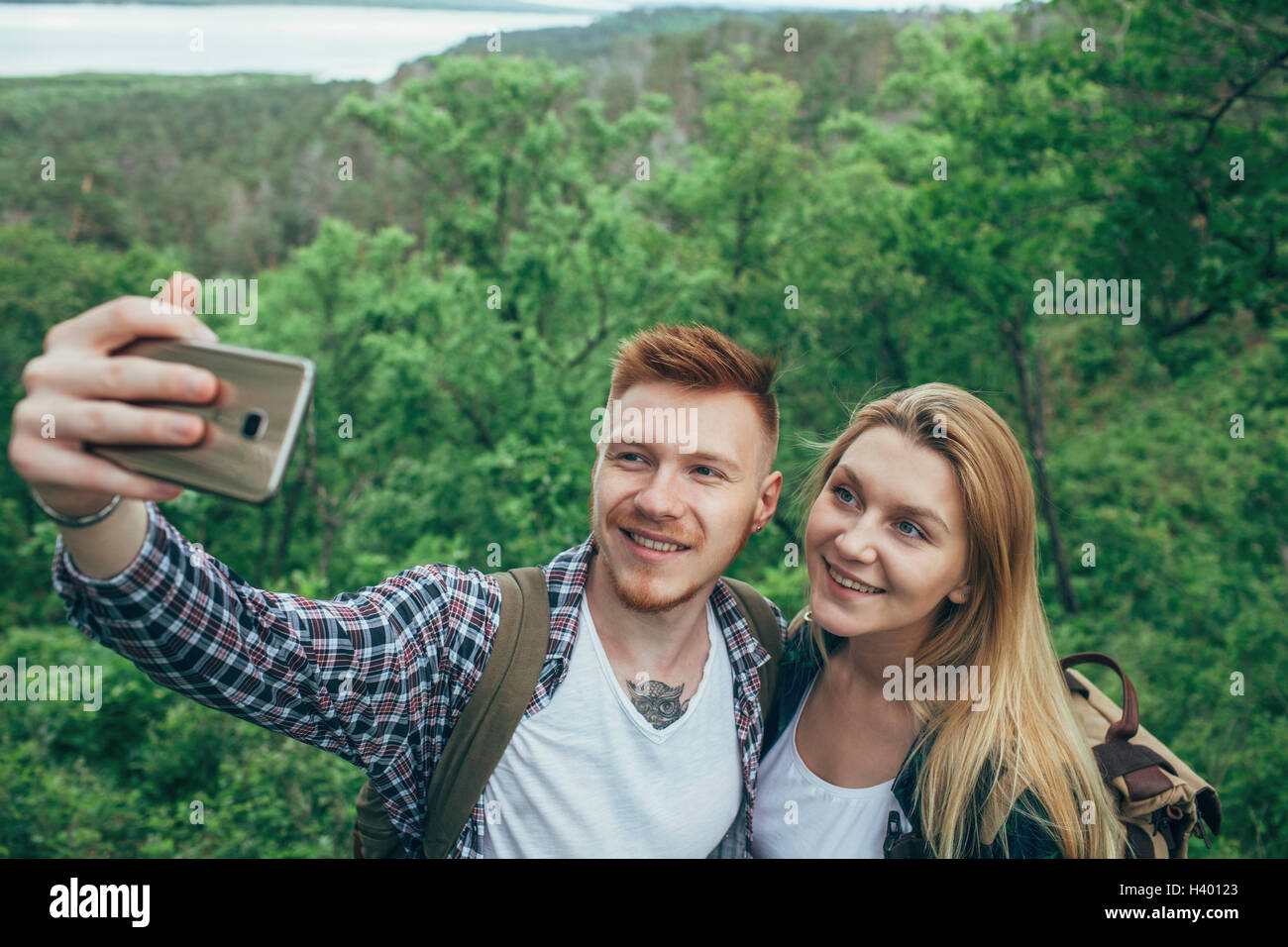 Coppia sorridente tenendo selfie attraverso smart phone a forest Foto Stock