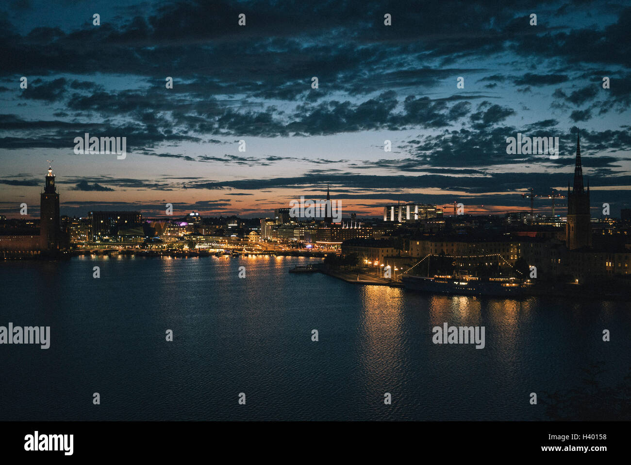 Vista panoramica del lungomare e la città illuminata contro il cielo al tramonto, Stoccolma, Svezia Foto Stock