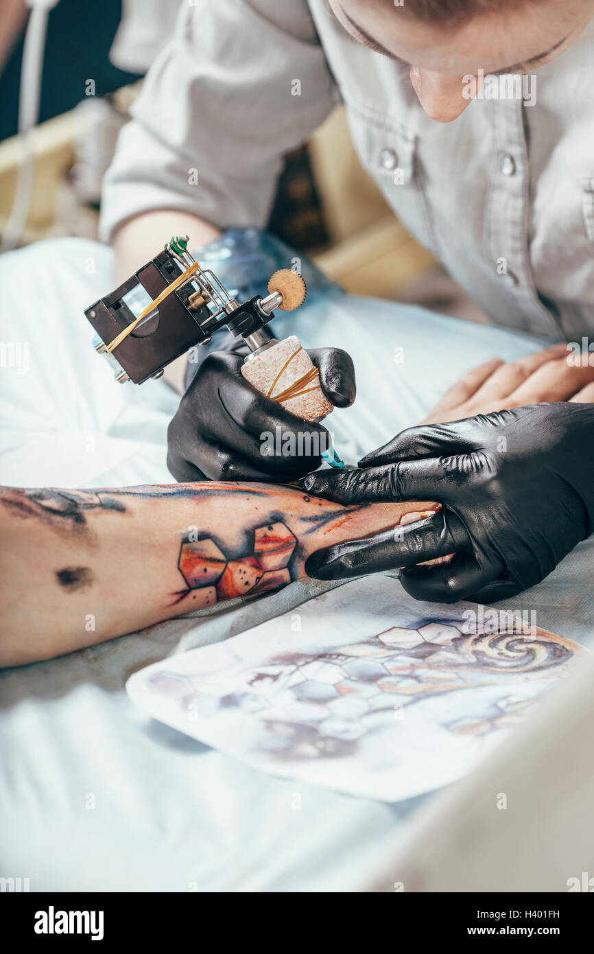 Artista concentrato tatuaggio disegno sulla mano umana Foto Stock