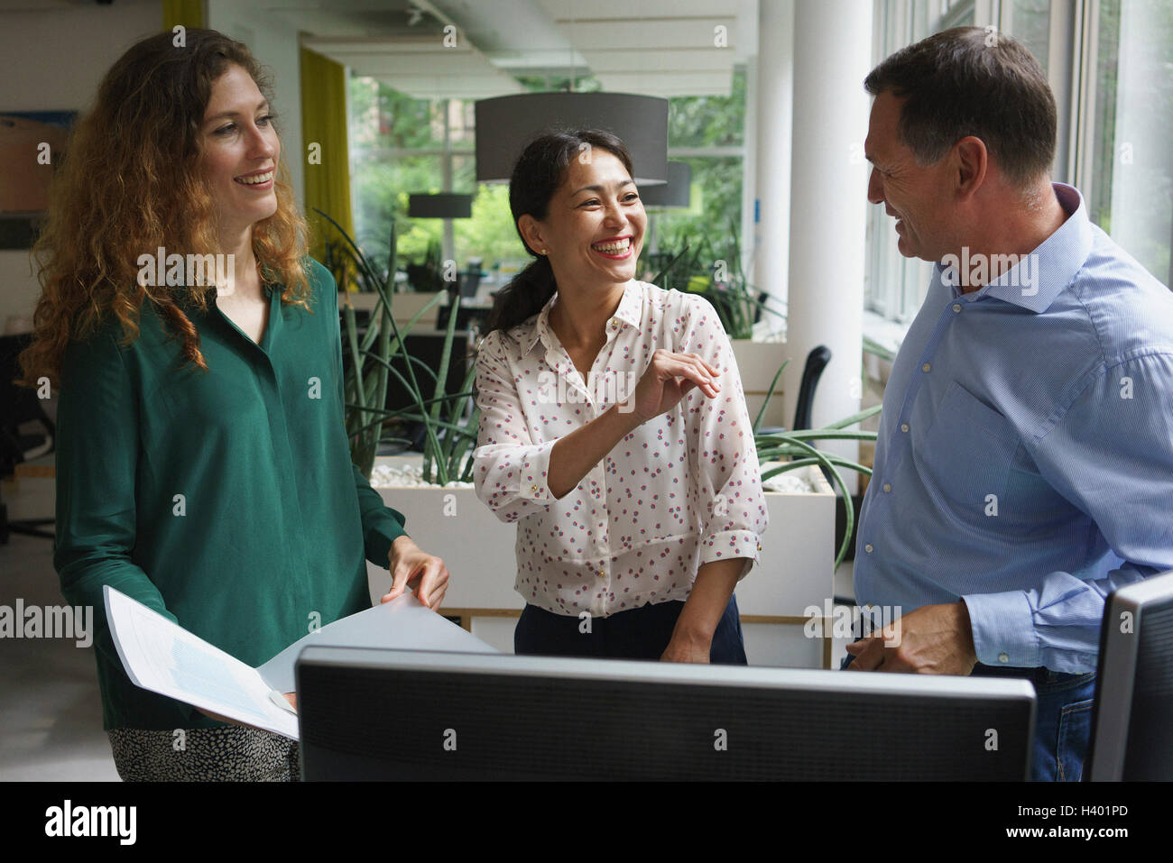 Happy business colleghi discutendo su documento alla scrivania in ufficio Foto Stock