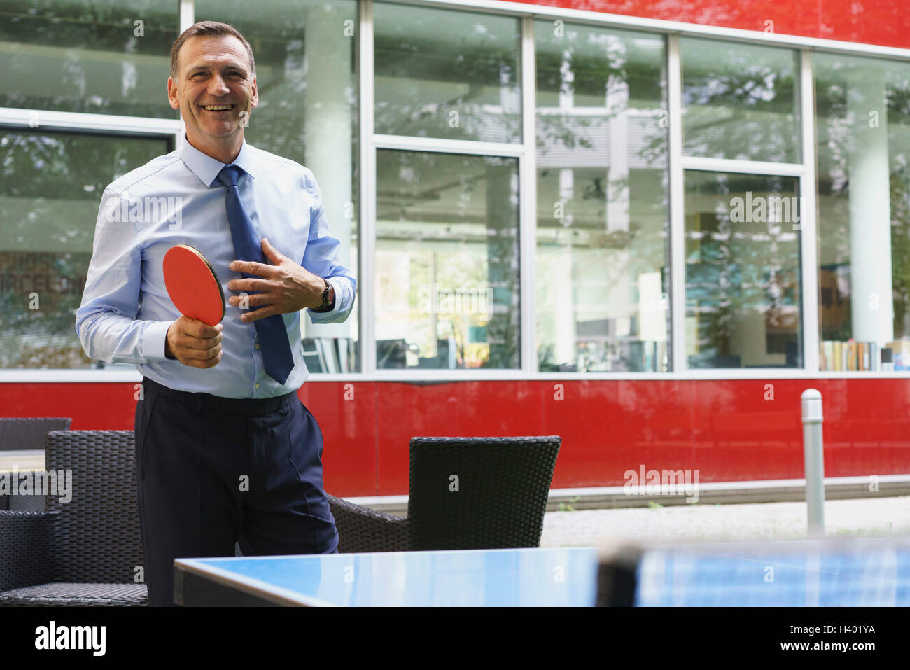 Sorridente persona d'affari giocando a ping-pong presso il creative office Foto Stock