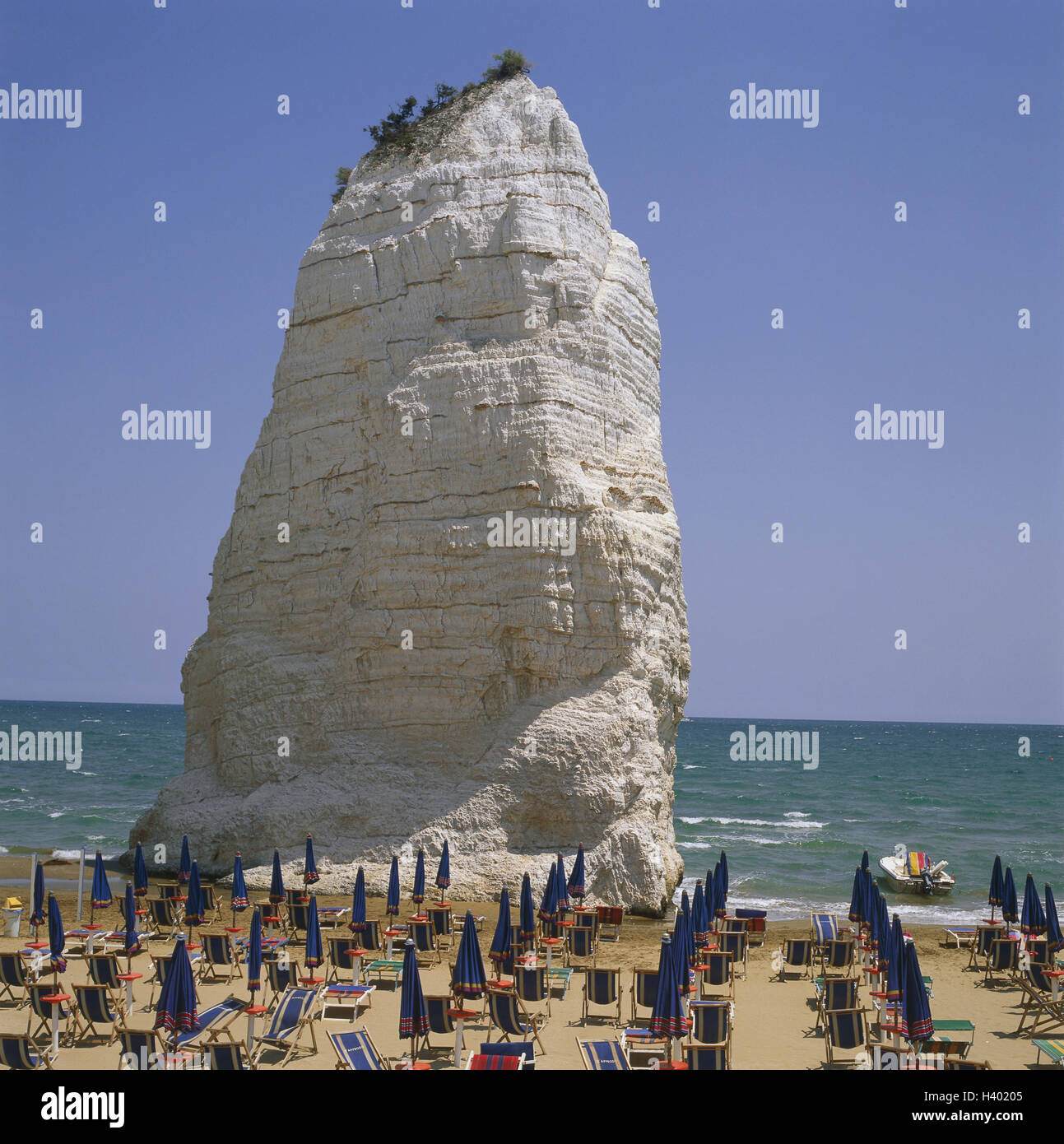 L'Italia, Puglia, Vieste, spiaggia, "Pizzomunno', spiaggia sabbiosa, sedie a sdraio, rock, formazione di bile, cielo blu, esterno Foto Stock