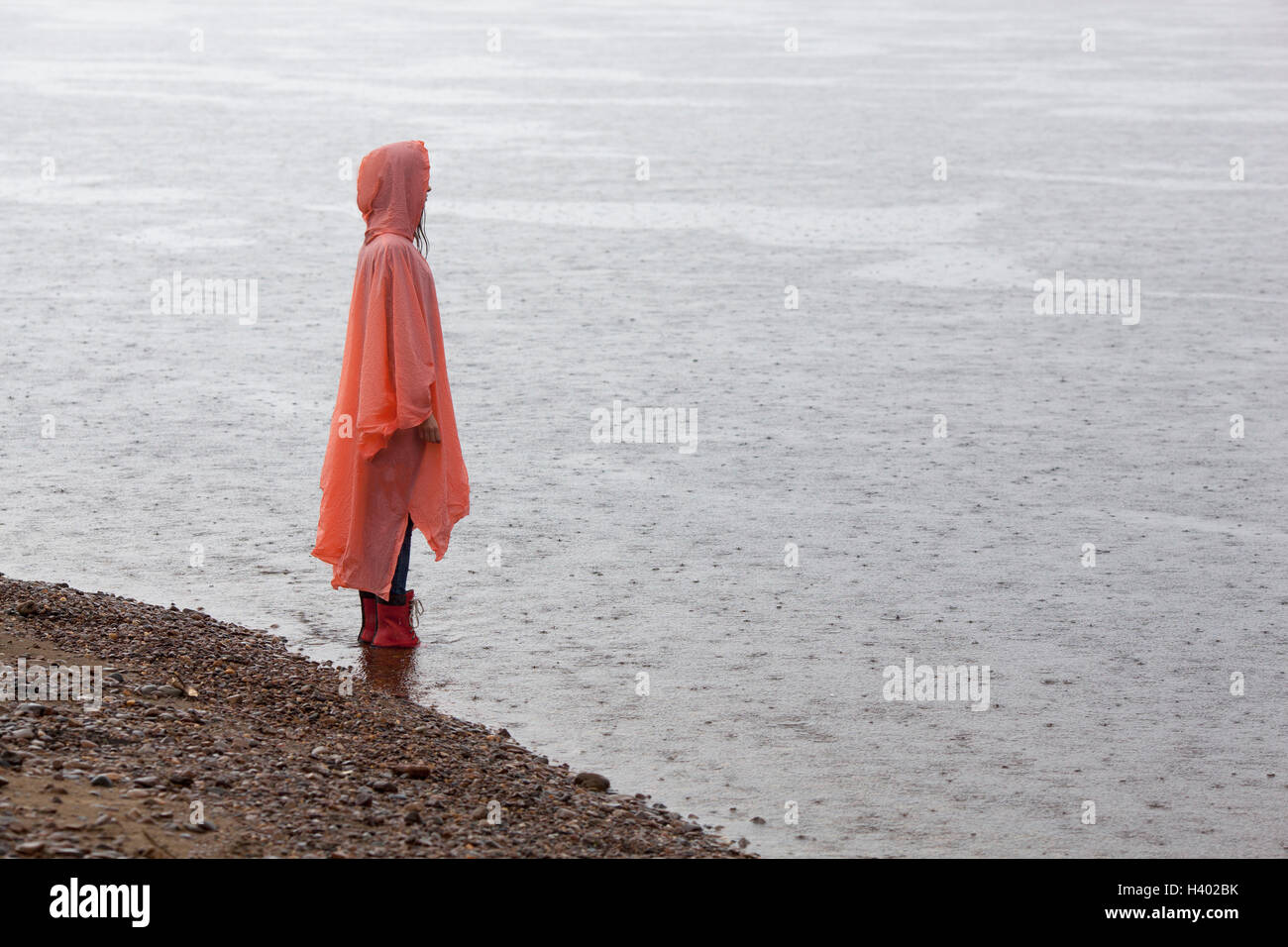 Donna che indossa un impermeabile in piedi sul lungolago durante la stagione delle piogge Foto Stock