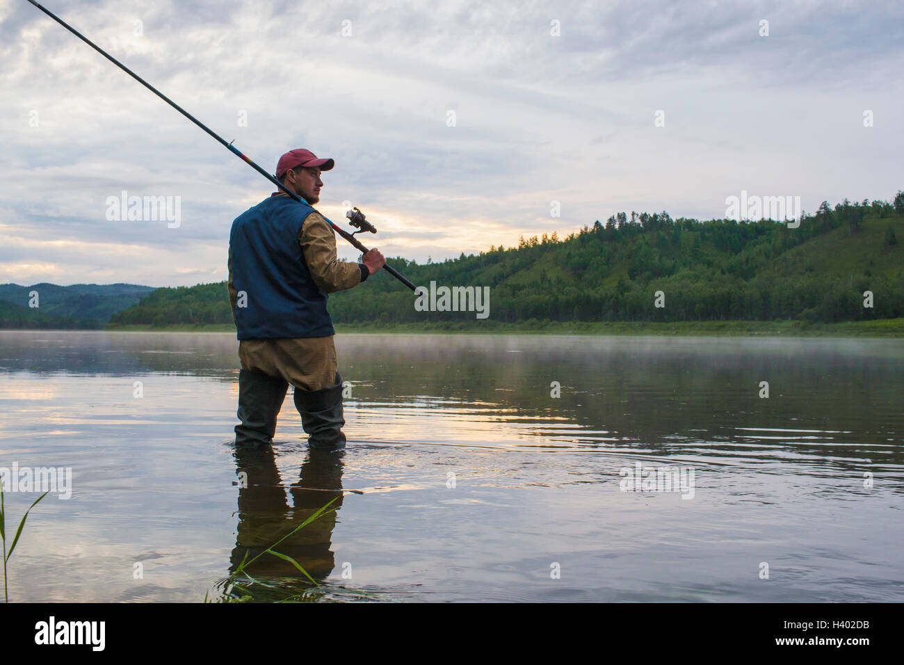 Uomo con asta di pesca mentre in piedi nel fiume contro sky Foto Stock