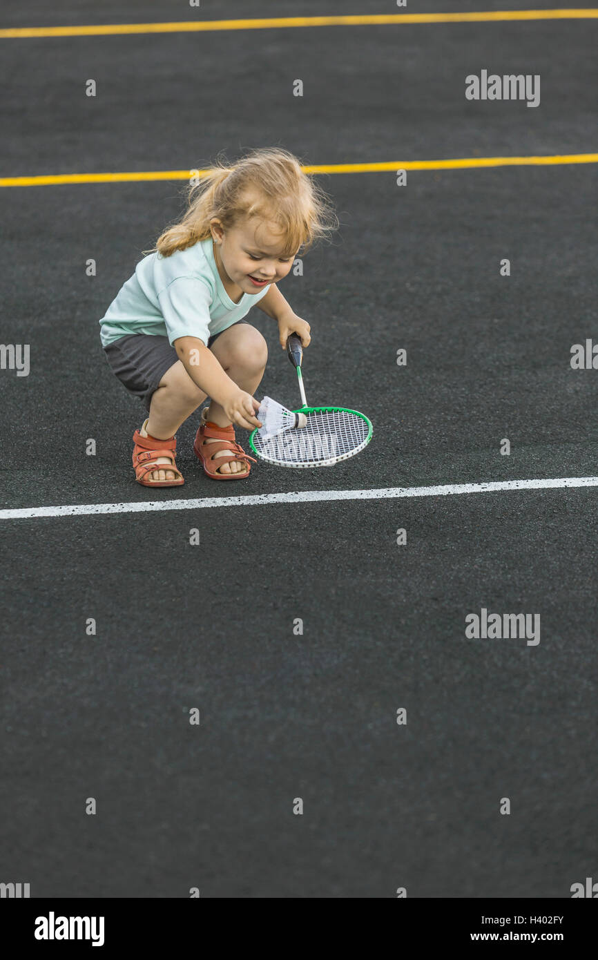 Felice ragazza che gioca con badminton racchetta e volano sul parco giochi Foto Stock