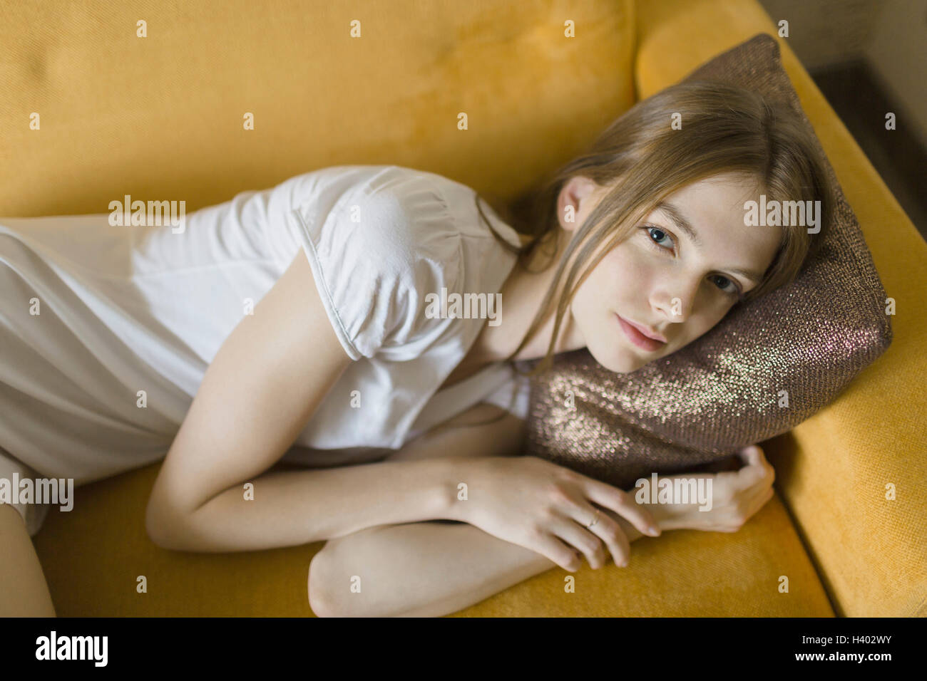 Angolo alto Ritratto di giovane donna appoggiata sul divano di casa Foto Stock