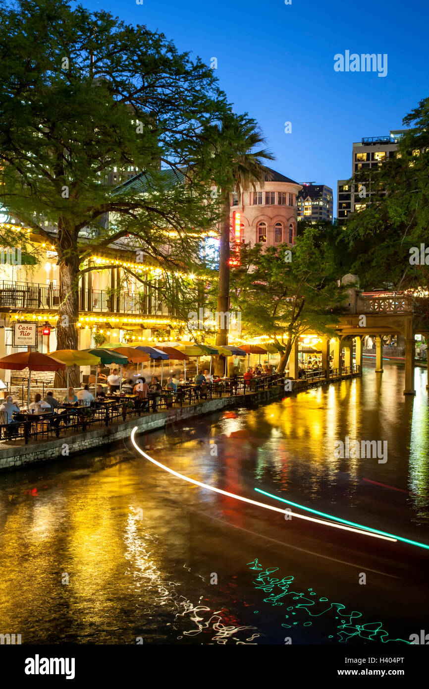 Ombrelloni colorati, barca striature chiare sul fiume San Antonio e il lungofiume di San Antonio, Texas, Stati Uniti d'America Foto Stock