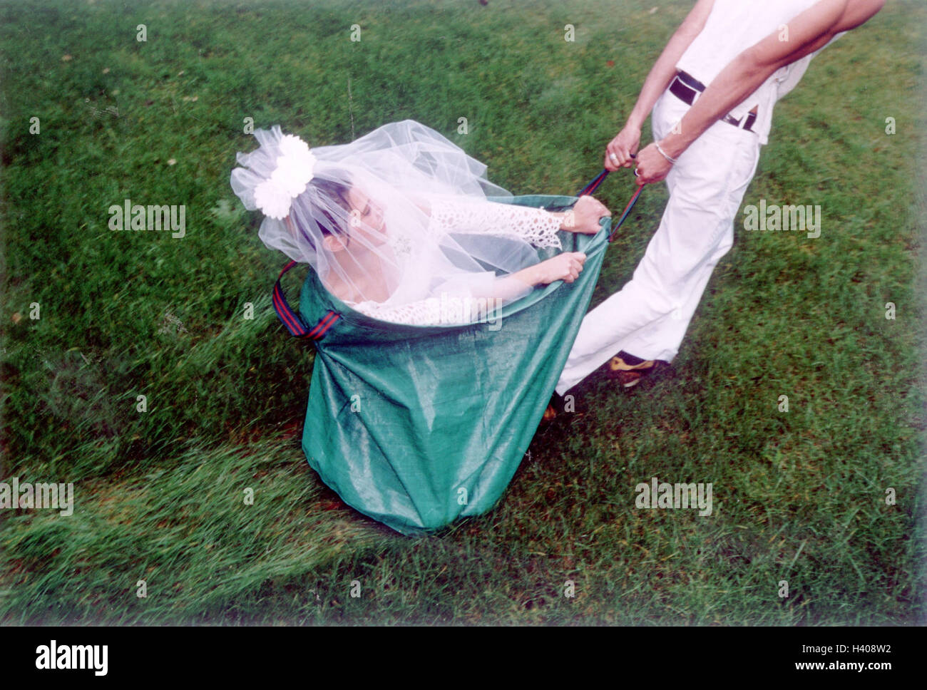 Prato, uomo, fogliame sacca, sposa, hinterherziehen, donna, Wedding, divertente, rapimento, sequestro nuziale, 'Brautverziehen', trascinare, borsa, custodia, verde, sedersi, wedding tag, matrimonio, felice, ridere, domanda divertente, esuberanza, pick up, carico, umorismo, trainare Foto Stock