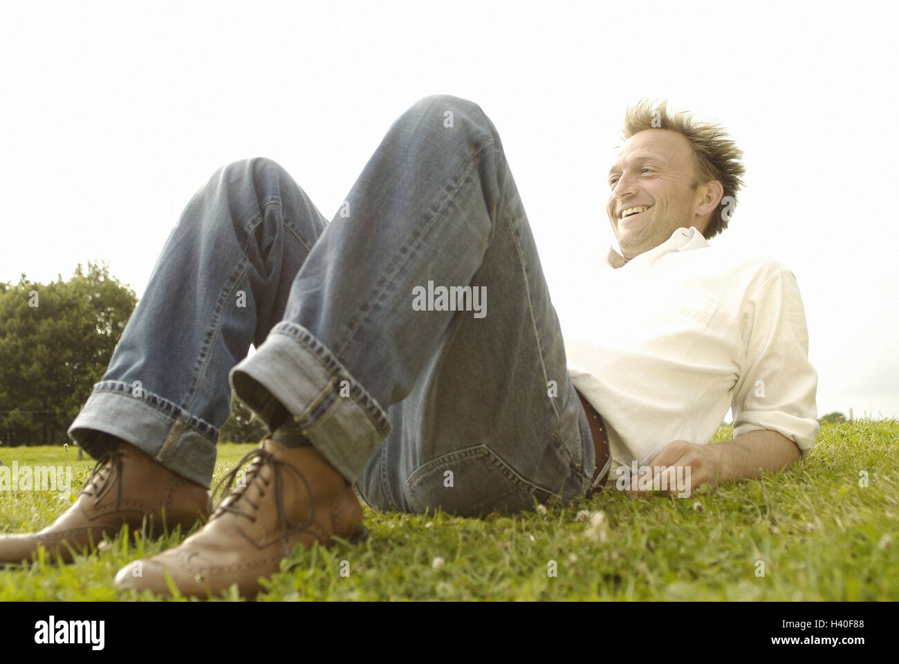Prato, uomo, ridere, giacciono, take it easy, vista laterale, 30-40 anni, contently, soddisfazione, ricreazione, di riposo e di godere di stile di vita, di riposo e di ossa prelevati, jeans, magliette, tempo libero, estate, esterno Foto Stock
