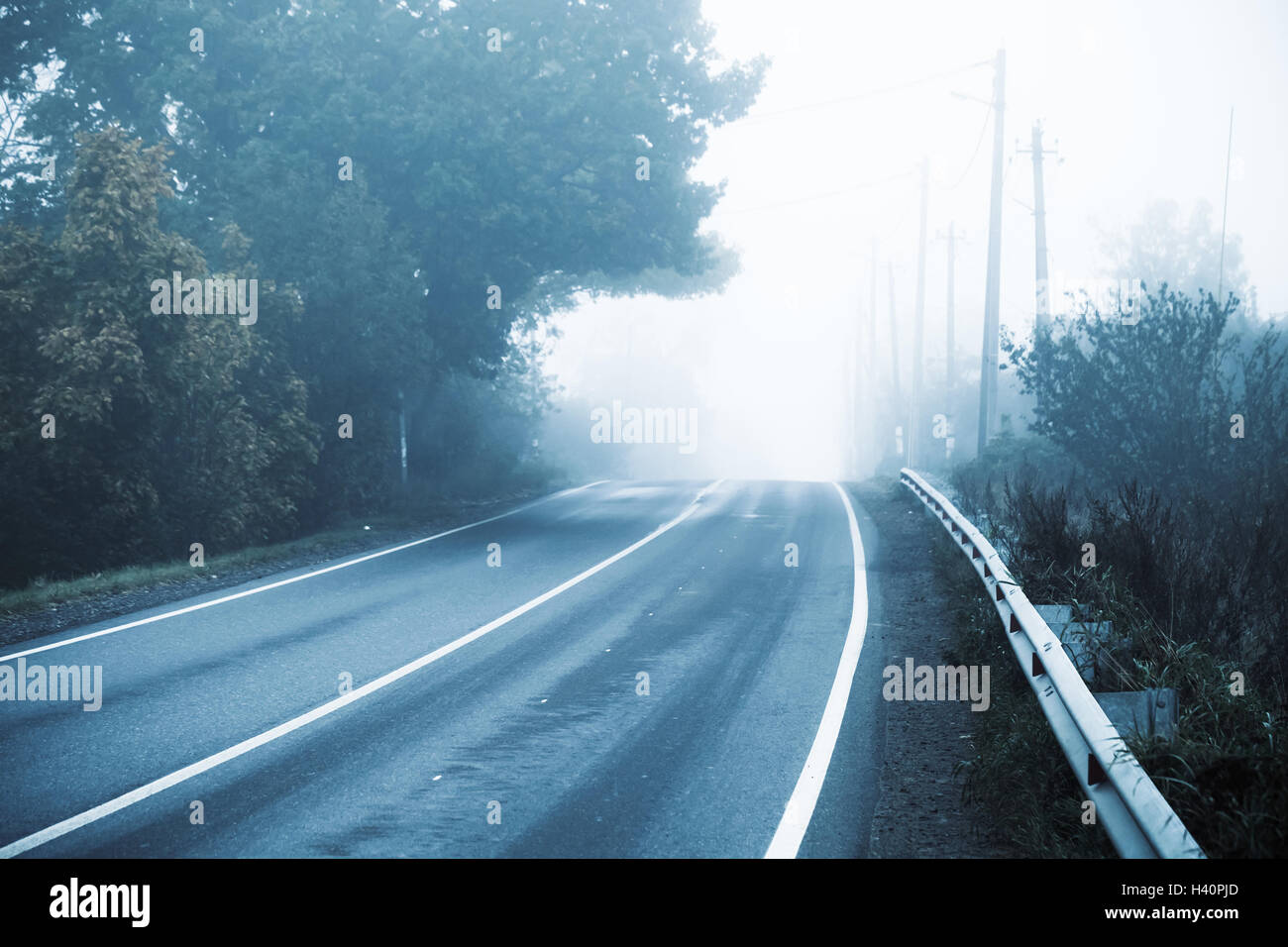 Vuoto autostrada rurale in autunno mattinata nebbiosa stilizzati foto con fredde tonalità blu correzione effetto filtro Foto Stock