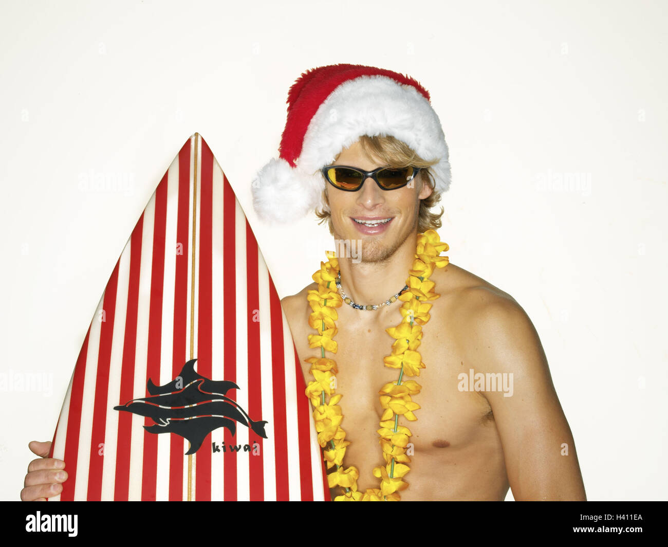 L'uomo, giovani, pantaloncini, tavola da surf, Santa's hat, ritratto, surfer, 20-30 anni, libera la parte superiore del corpo, fiore catena, fiore catena, occhiali da sole, tavola da surf, icona, vacanze, tempo libero e vacanze di Natale, riposo e ricreazione, Natale, passato il Natale str Foto Stock