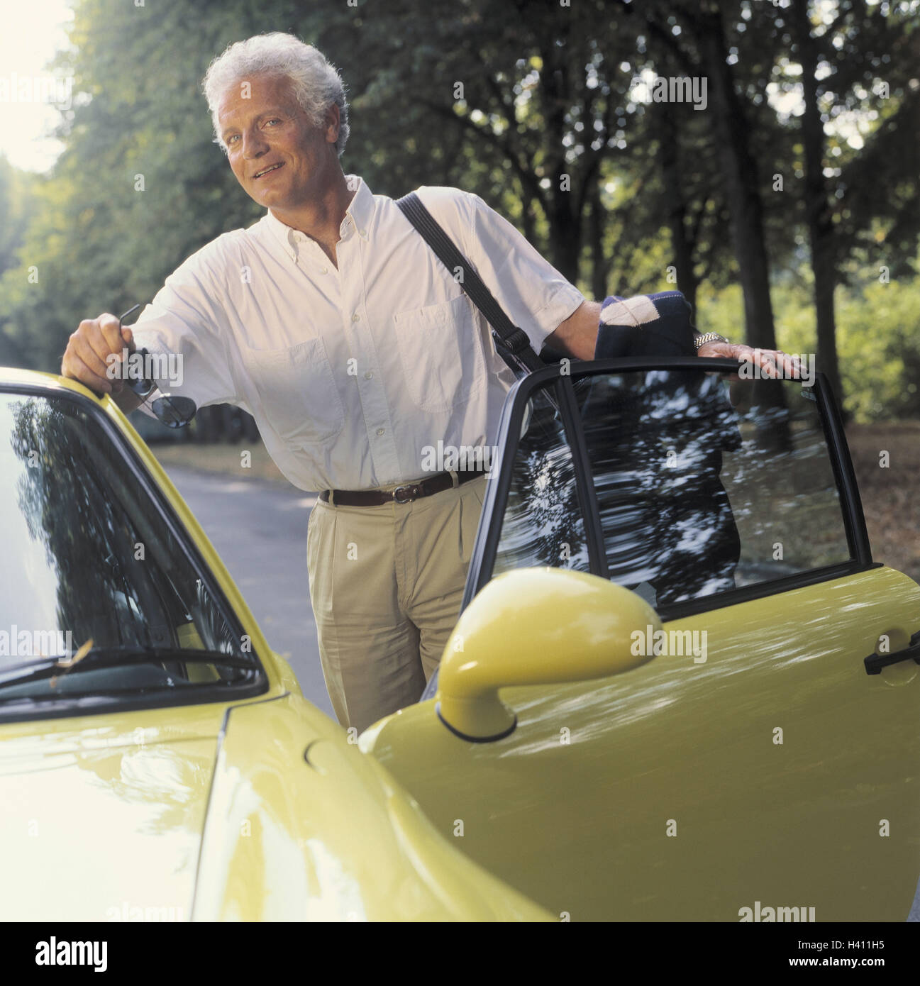 L'uomo, sorridere medio persona vecchia, Porsche, palo in attesa, 40-50 anni, grigio-pelose, imprenditore, ben-to-do, ricchezza, di lusso auto di lusso, autovetture, sports car porta conducente, aperto, custodia, occhiali da sole, allegria, soddisfazione, estate, esterno, lei Foto Stock