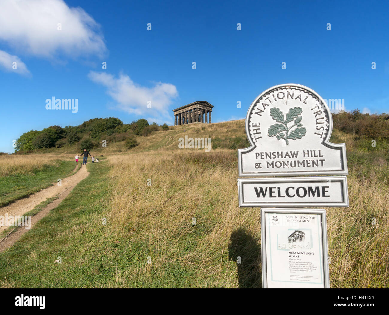 Il National Trust segno per Penshaw monumento con la famiglia a piedi in background, England, Regno Unito Foto Stock