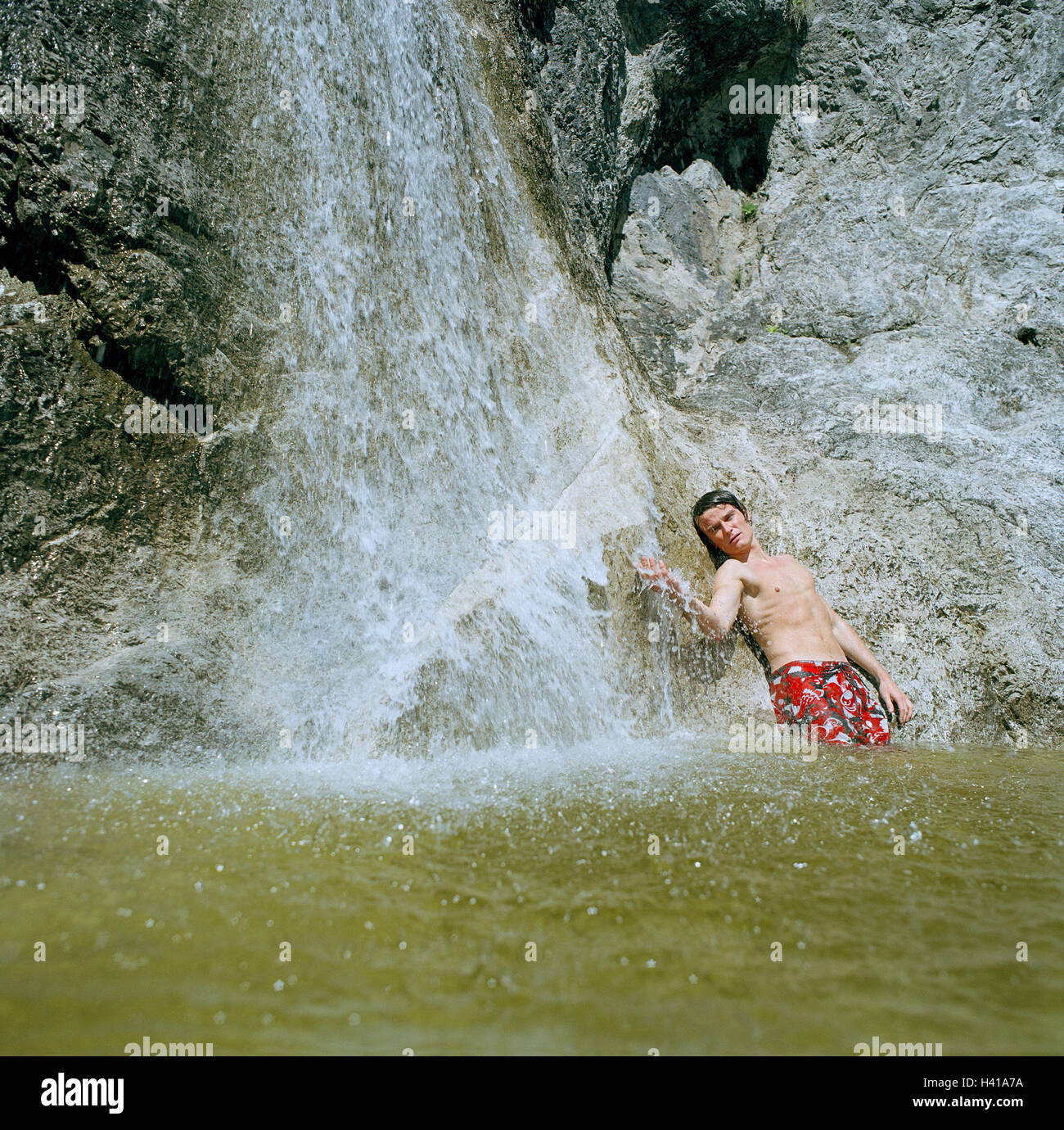 Cascata, uomo, giovani, nuoto tronchi, rock, magro, gesto, 23 anni, gioventù, sogni lontano, costumi da bagno, pantaloncini, libera la parte superiore del corpo e del tempo libero, estate, natura, godere, appoggia, raffreddamento, ristoro, acqua, fiume, l'Isar, Isar prati, fessura anteriore Foto Stock