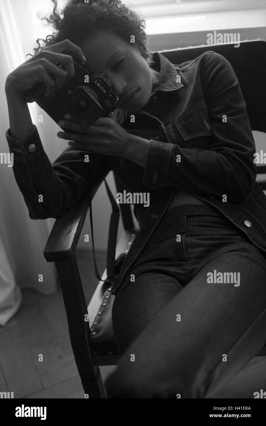 Poltrone, donna, scattare foto, b/w, giovane, di carnagione scura, capelli ricci, ondulata, fotocamera, foto fotocamera, fotografo, occupazione, tempo libero, hobby, attività, all'interno, lo stile di vita Foto Stock