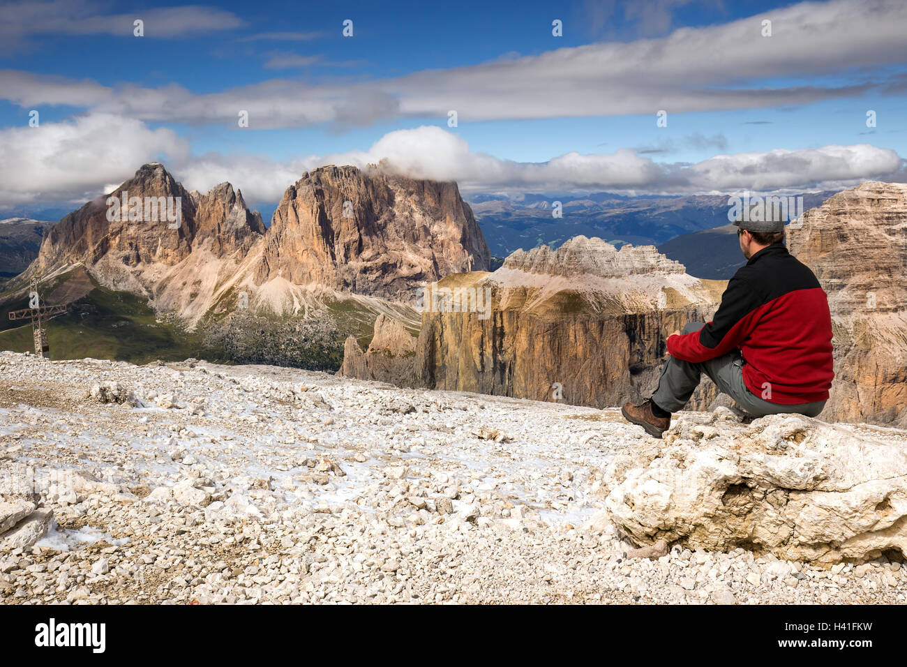 Giovane uomo guardando il gruppo Sella mountain range dal Sass Pordoi, Dolomiti, Italia, Europa Foto Stock