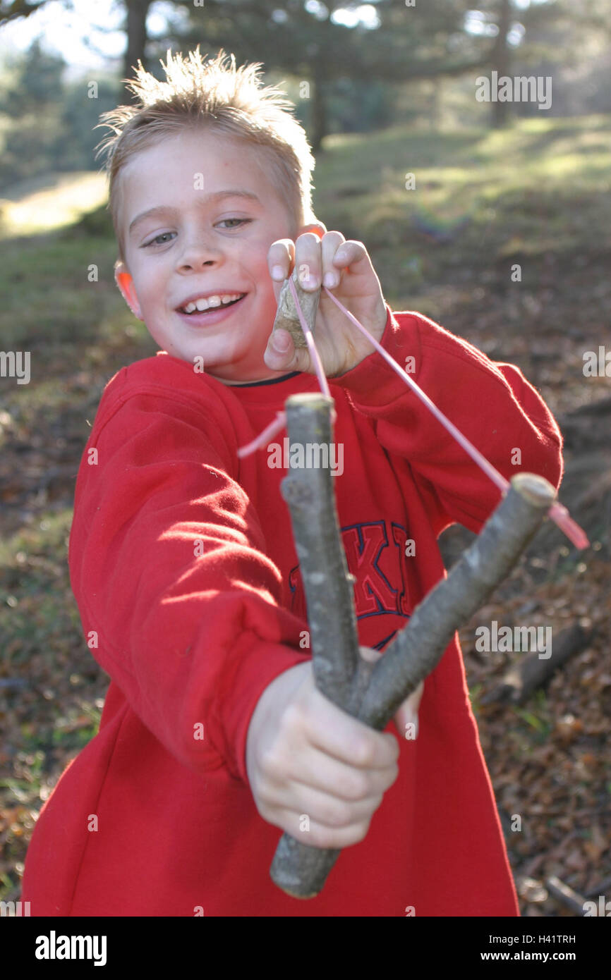 Il ragazzo, catapulta, AIM, play legno ritratto, stagione autunno, autumnally, bosco di latifoglie, bambino, infanzia, 4 - 9 anni, arma, pietra, pericolosamente, ridere, sparare, pericolo di pregiudizio, esterno, rascal, spike boy, pidocchio di jack, rogue, roguishly Foto Stock
