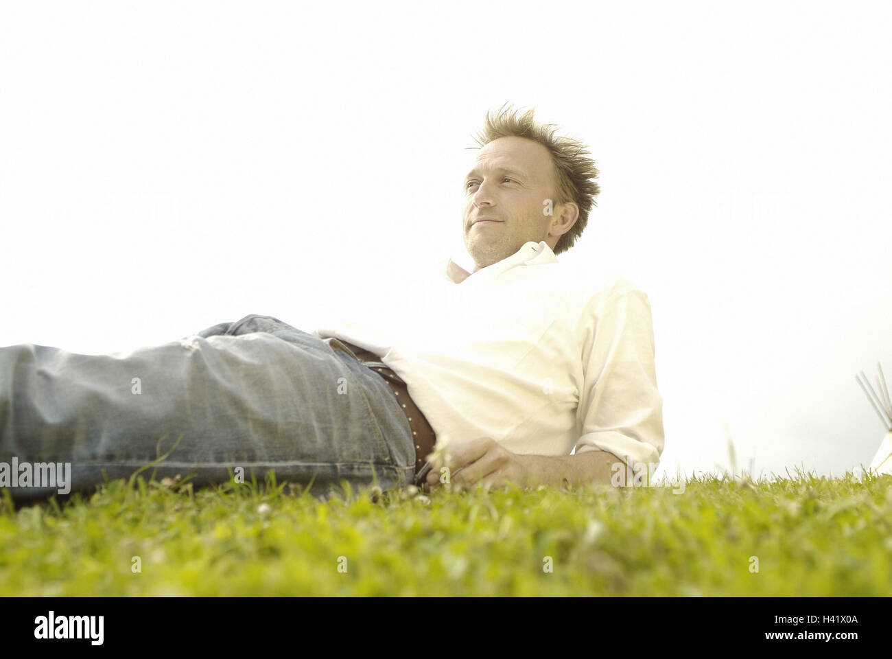 Prato, uomo, sorriso, giacciono, take it easy, vista laterale, 30-40 anni, contently, soddisfazione, ricreazione, di riposo e di godere di stile di vita, riposo, jeans, magliette, tempo libero, le estati, esterno Foto Stock