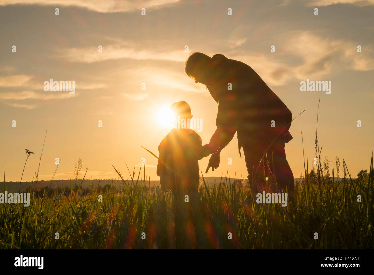 La donna e il figlio in piedi in campo al tramonto Foto Stock