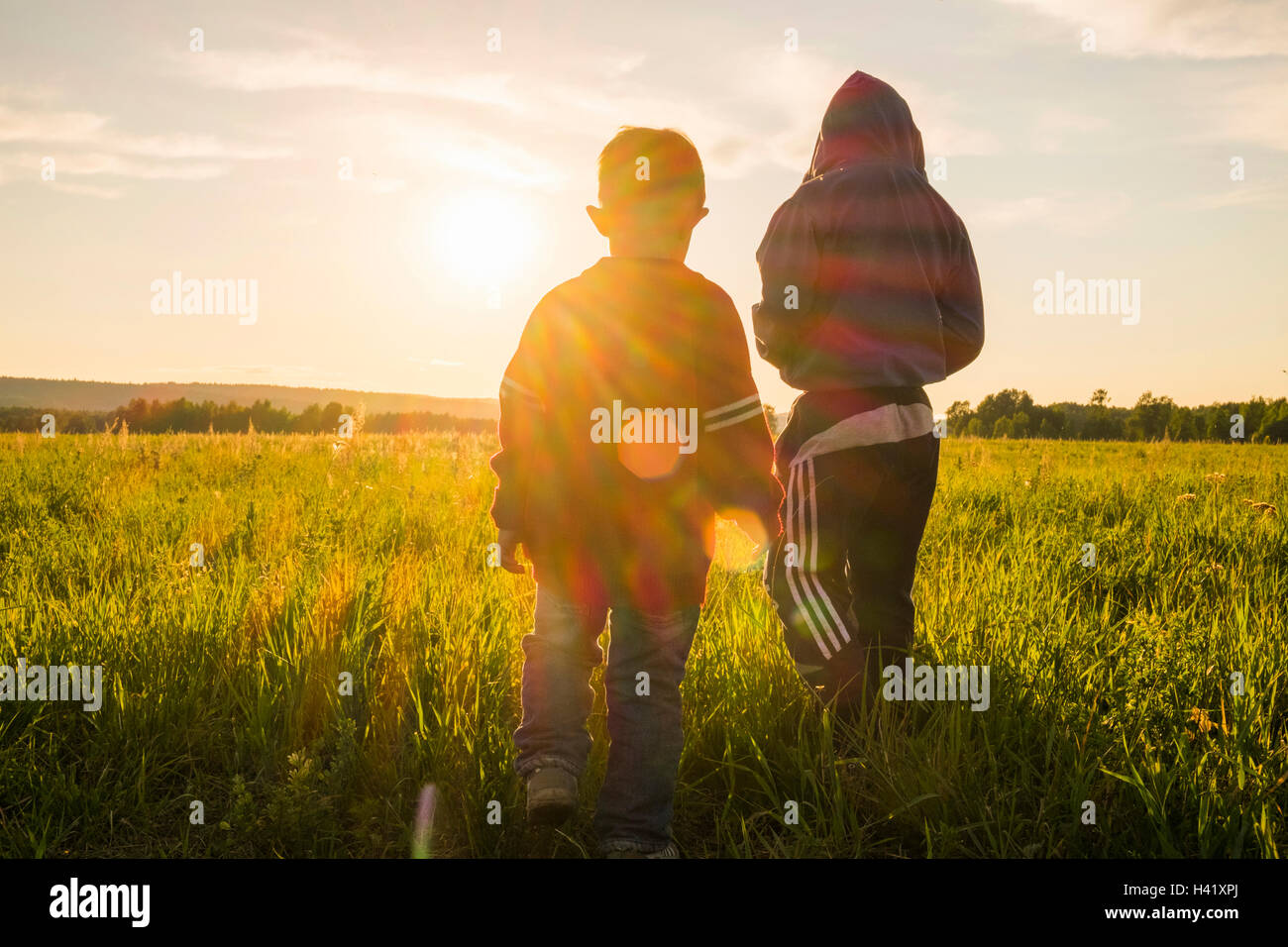 Mari ragazzi camminare in campo al tramonto Foto Stock