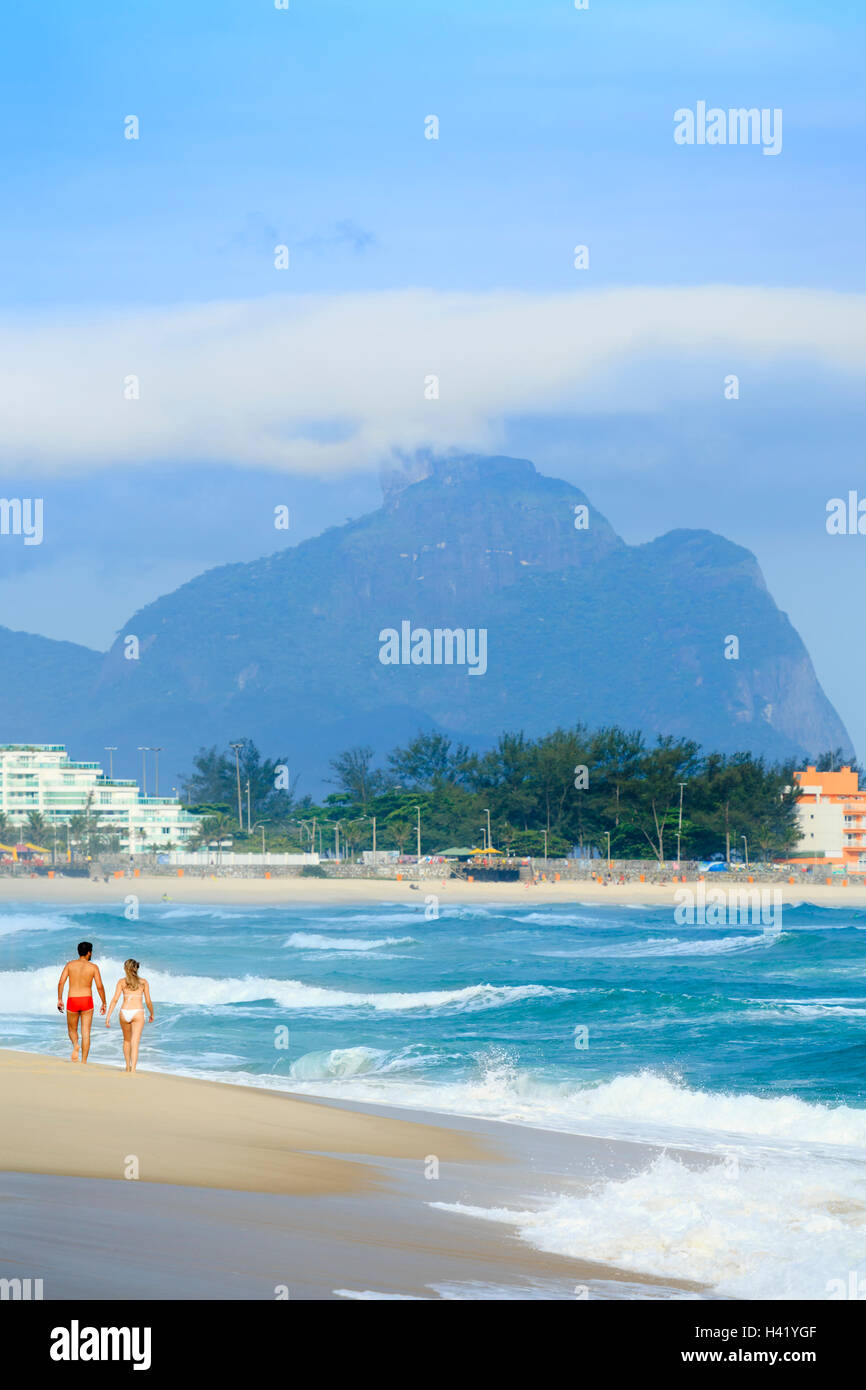 Giovane camminando sulla spiaggia nei pressi delle forme d'onda Foto Stock