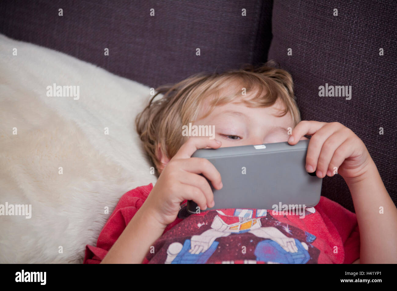 Ragazzo caucasico posa sul divano guardando telefono cellulare Foto Stock