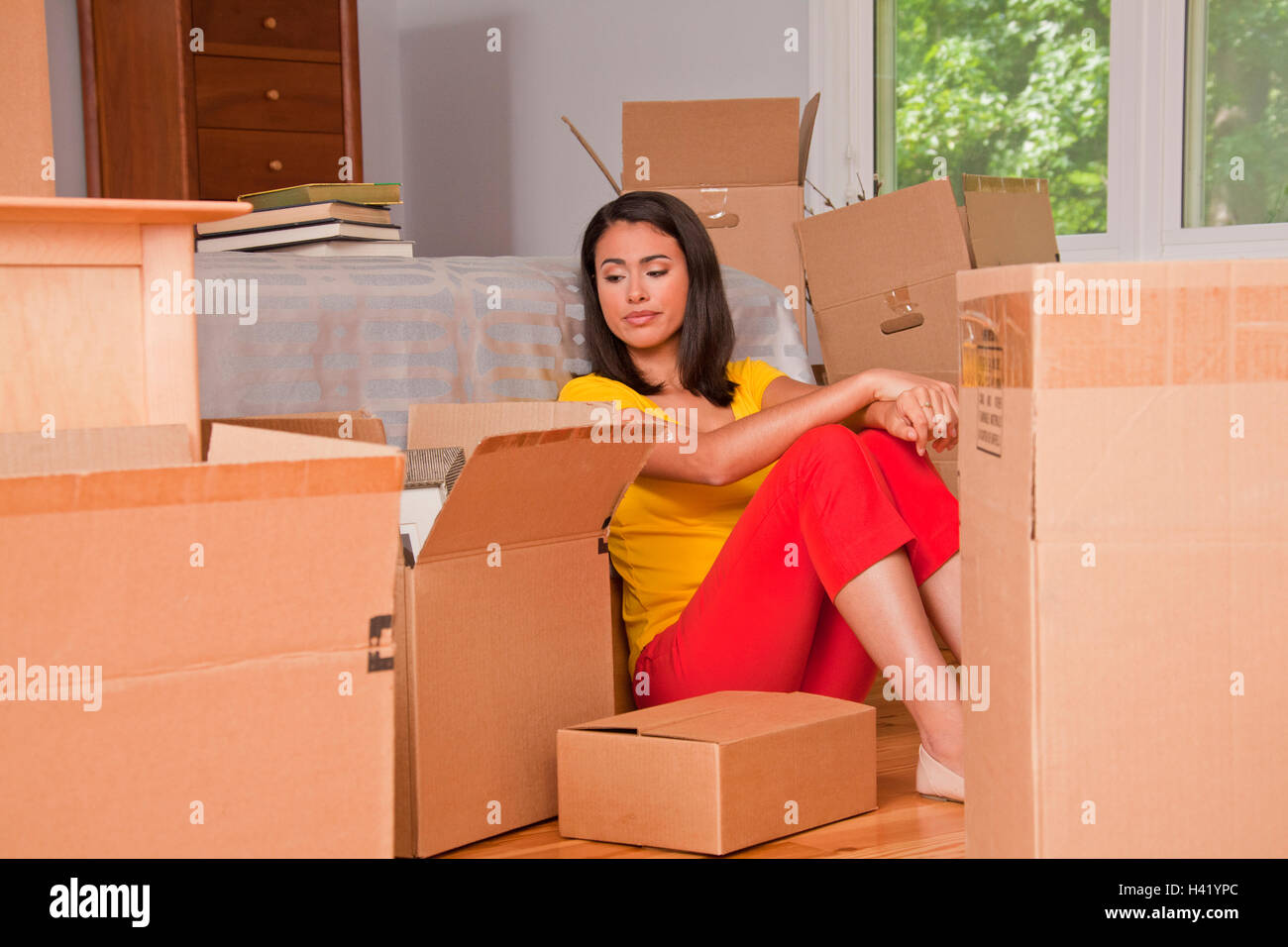 Ispanico donna seduta sul pavimento con contenitori per il trasloco Foto Stock