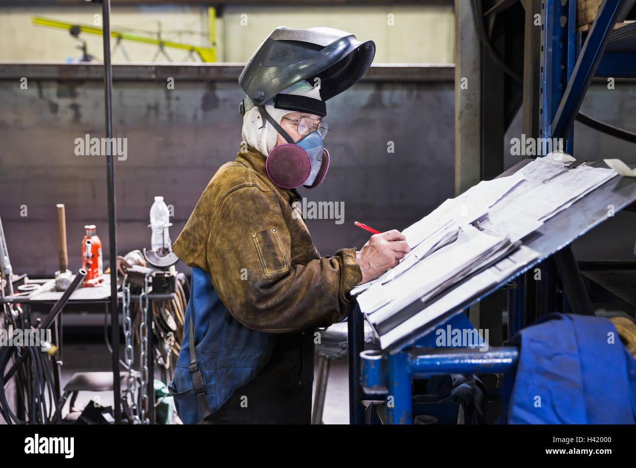 Asian Lavoratore che indossa la maschera sulla scrittura di documenti cartacei in fabbrica Foto Stock