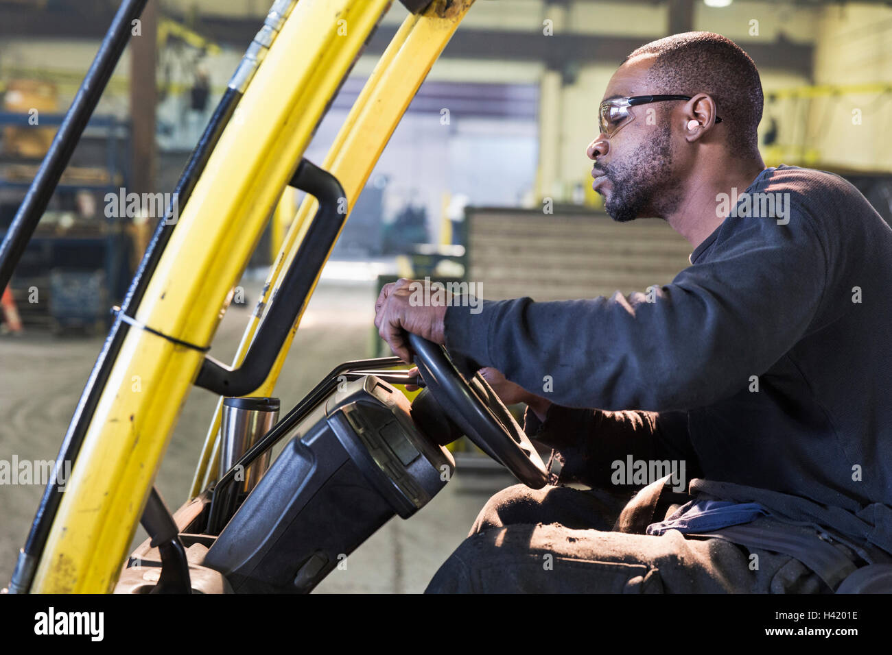 Lavoratore nero la guida carrello in fabbrica Foto Stock