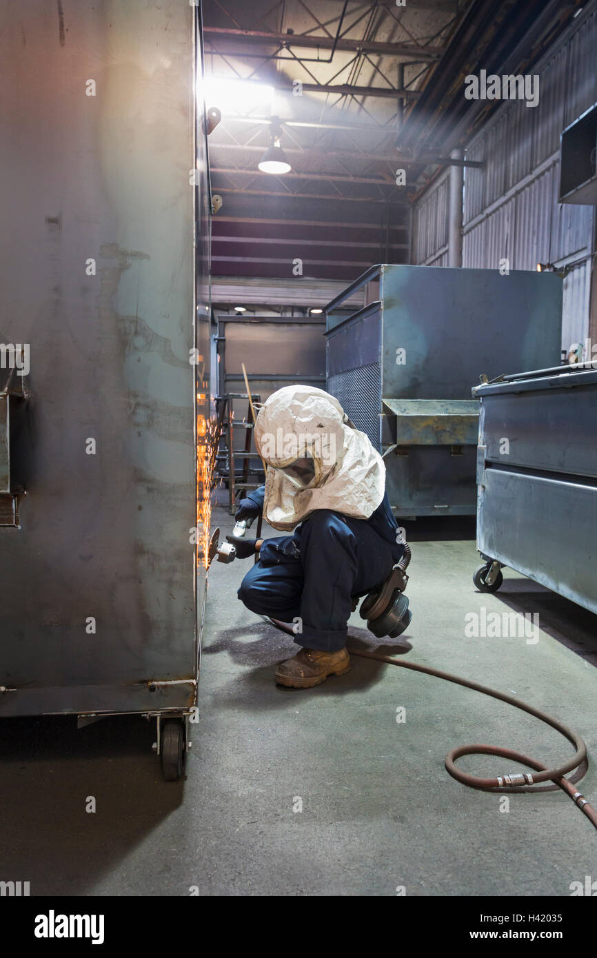 Lavoratore caucasica macinazione di contenitore metallico in fabbrica Foto Stock