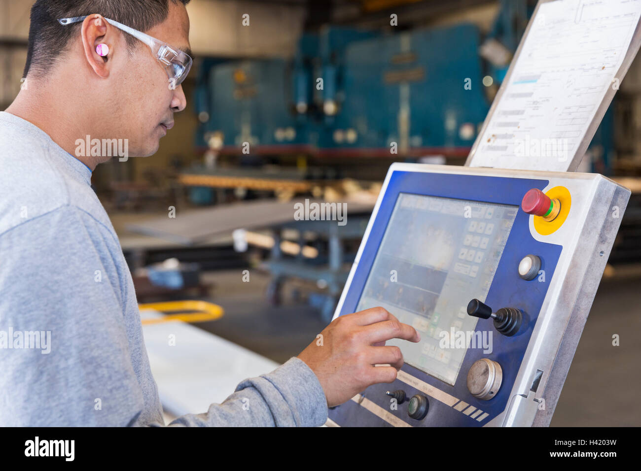 Asian lavoratore utilizzando il pannello di controllo in fabbrica Foto Stock