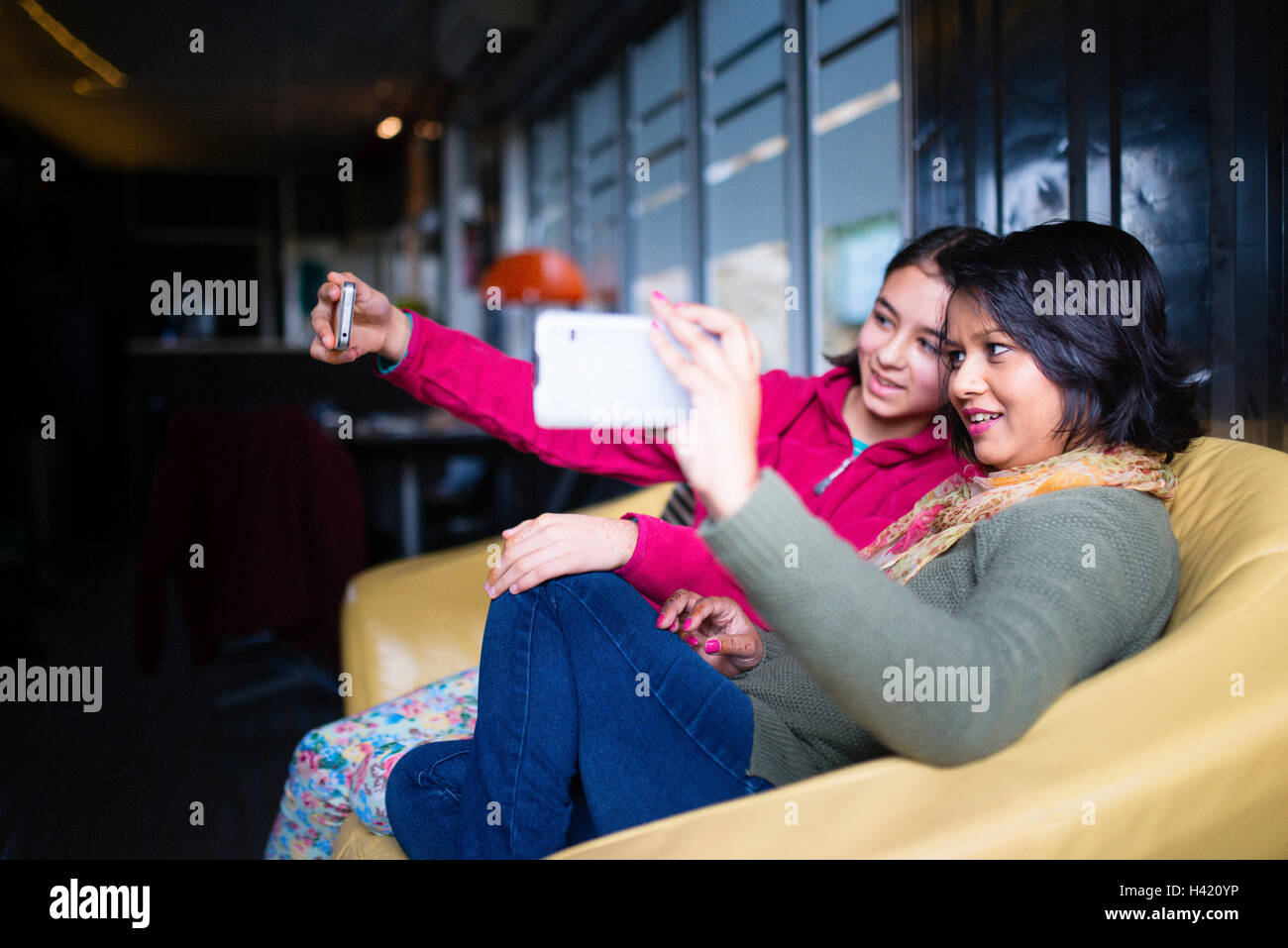 Madre e figlia seduti sul divano in posa per telefono cellulare selfie Foto Stock
