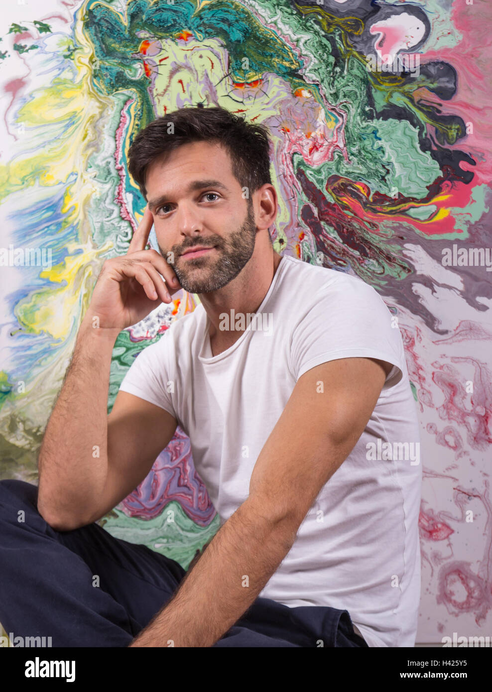 Giovane artista pittore in posa davanti astratta pittura colorata Foto Stock