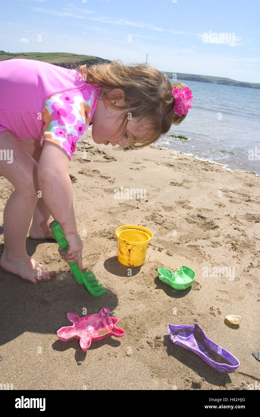 Spiaggia, ragazza, poca sabbia forma, giocare, bambino, infanzia, 2 anni, tempo libero e felice, gioco, attività, sabbia, spiaggia sabbiosa, poco forma, giocattoli, sabbia giocattoli, vacanze, ferie, estate, all'esterno, sul mare, Devon, Inghilterra, Gran Bretagna Foto Stock