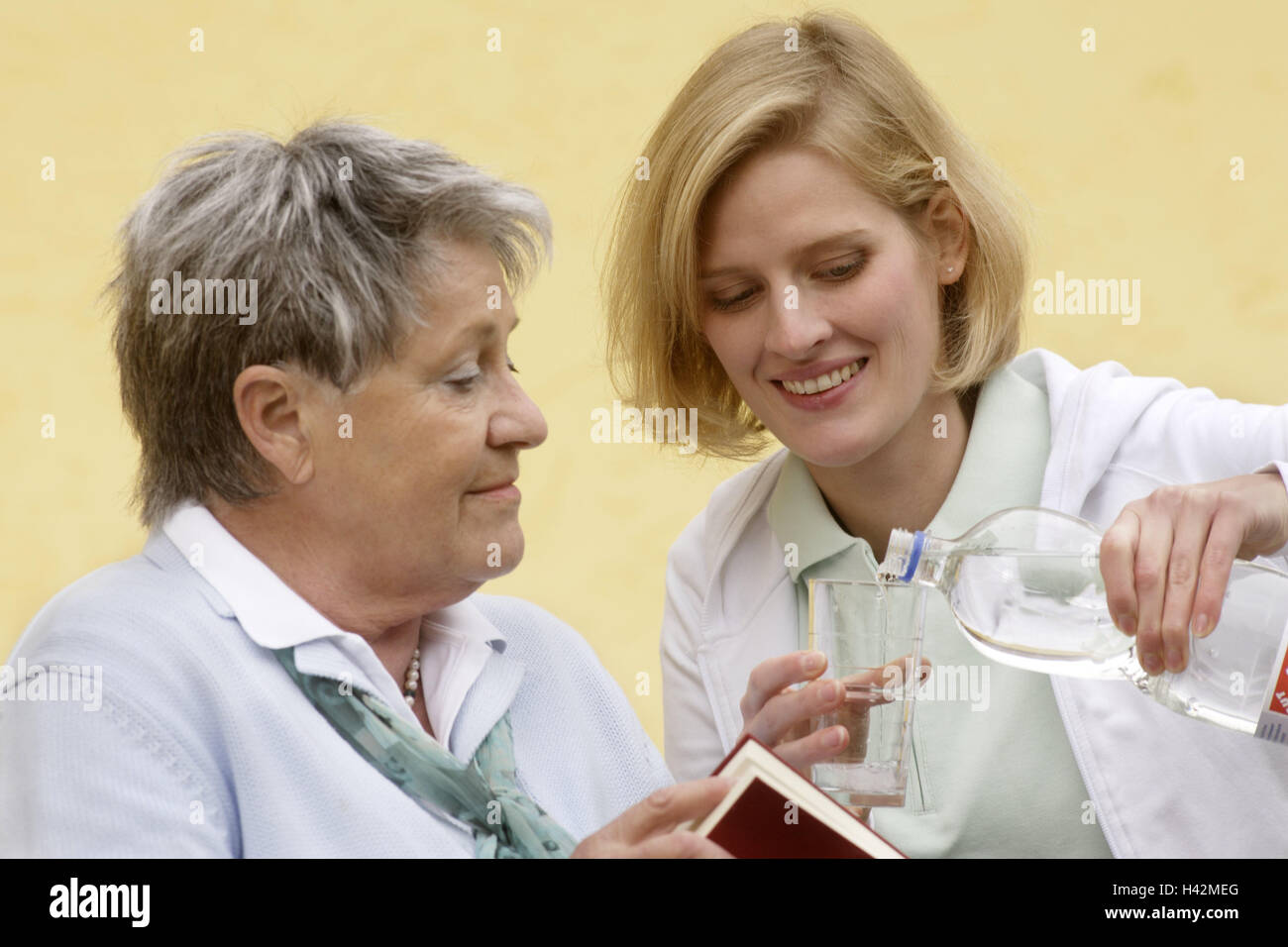 Senior, libro, vecchio infermiere, sorriso, versare in vetro, acqua, ritratto, Senior Citizen's home, vecchia casa di riposo, servizio, persona, vecchi e giovani, professione, due donne, infermiere, Pflegeporsonal, titolare di pensione o di rendita, attivamente, agile, attivo in bisogno di cure, coltivati, cittadini anziani, generazioni, sete, bicchiere di acqua, bevande, riempimento, vetro, assistenza, alimentazione, visita, la cura, la sutura, assegno, supporto, attenzione, cura, felice, all'interno, Foto Stock