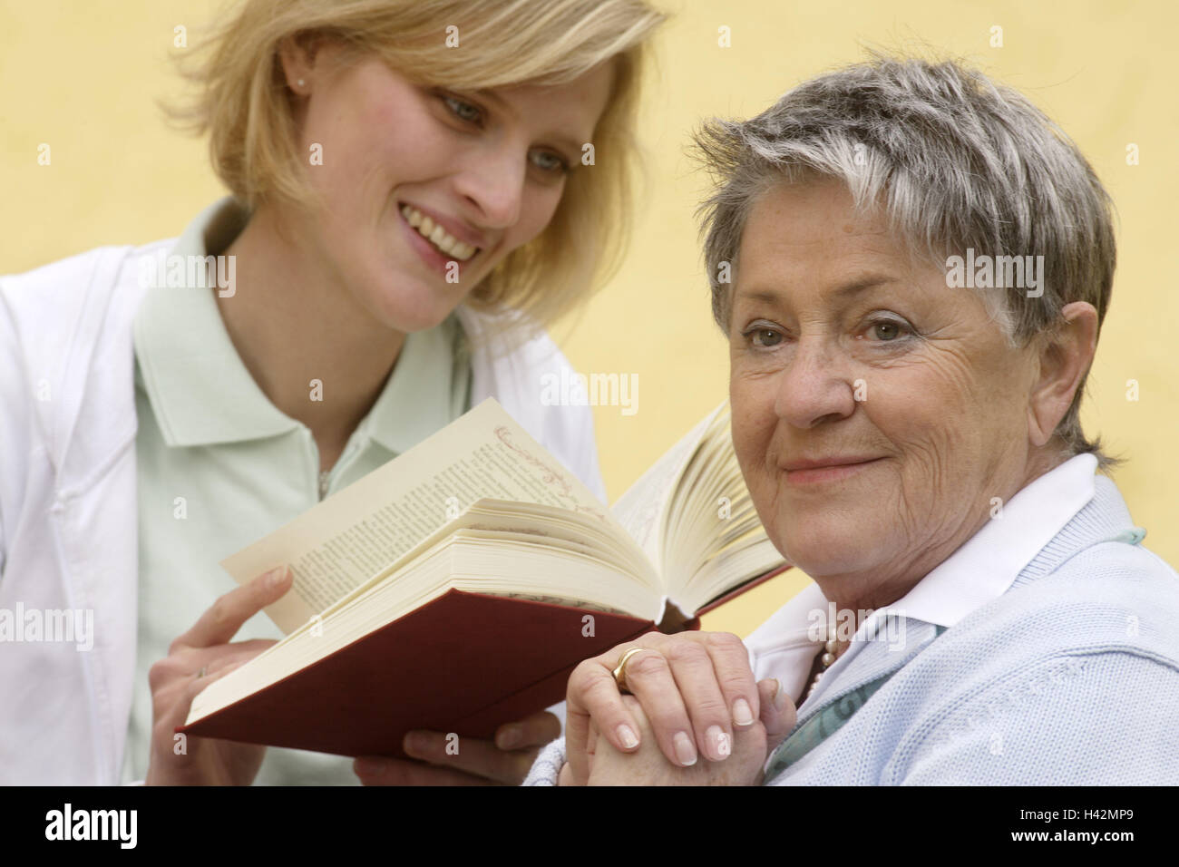 Senior, vecchio infermiere, felice, sorridere leggere il libro, ritratto, Senior Citizen's home, vecchia casa di riposo, servizio, persona, vecchi e giovani, professione, due donne, infermiere, Pflegeporsonal, titolare di pensione o di rendita, attivamente, agile, attivo in bisogno di cure, coltivati, cittadini anziani, generazioni, la cura, la sutura, contatto, indennità, supporto, attenzione, cura, intrattenimento, leggere la letteratura, noia, romana, gioia, visita, supporto, interessi affettuosamente, felice, ascoltare, ascoltare, all'interno, Foto Stock