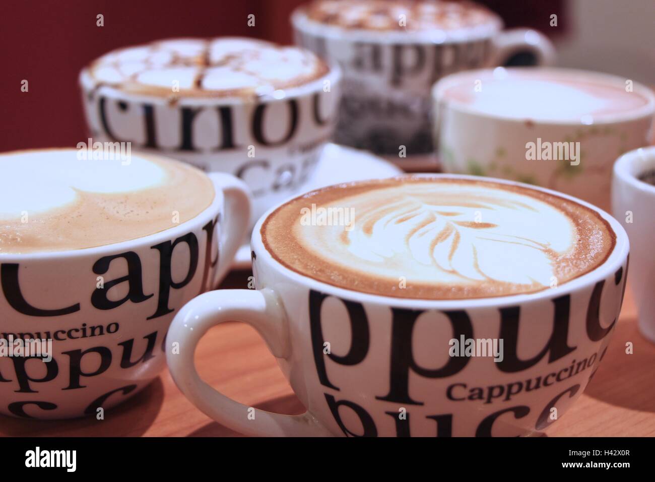 Quattro tazze di cappuccino con schiuma decorato e bokeh di fondo Foto  stock - Alamy